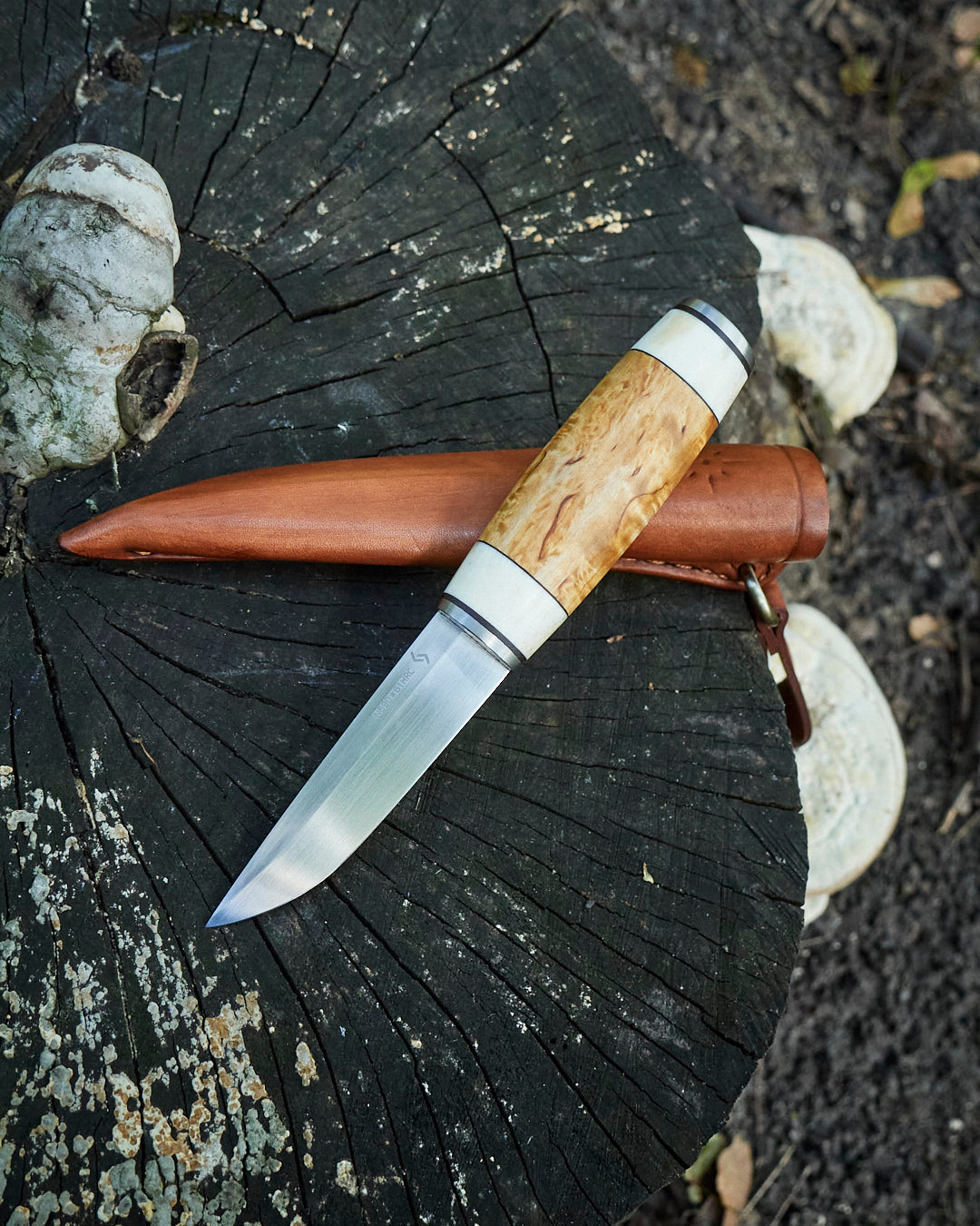 The hand made puukko, n690 blade, curly birch/antler handle, leather sheath.