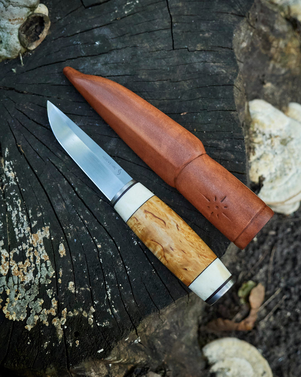 The hand made puukko, n690 blade, curly birch/antler handle, leather sheath.