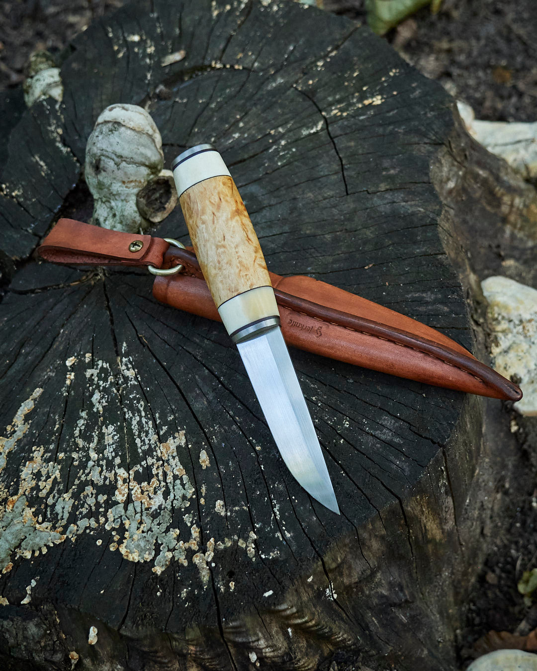 The hand made puukko, n690 blade, curly birch/antler handle, leather sheath.